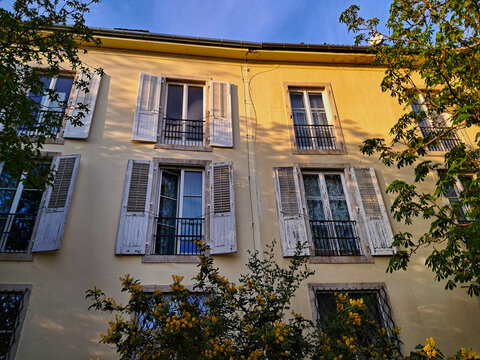 Traditional yellow facade of a Budapest building near Toth Arpad Promenade, featuring classic windows with white wooden shutters.