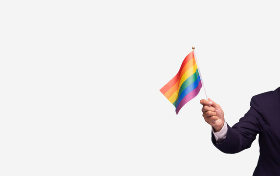 Hand holding rainbow flag symbolizing LGBTQ pride