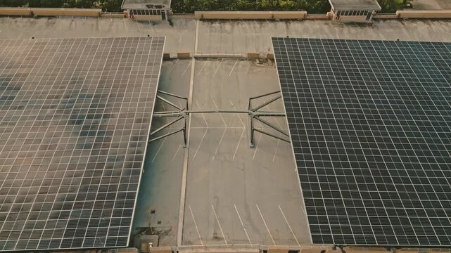 Twin photovoltaic panel structures generating electricity for smart hydrogen microgrid bordering empty parking lanes on concrete rooftop captured via slow reverse ascending drone perspective