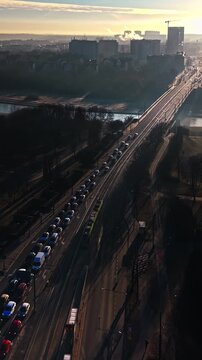 Public transportation train moving city traffic skyline sunset urban landscape. Modern passenger railway transport blurred motion street vehicle congestion high angle view. Golden hour sunlight haze