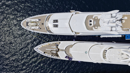 Aerial drone top down photo of latest technology mega yachts with luxurious wooden stern anchored in deep blue sea © aerial-drone