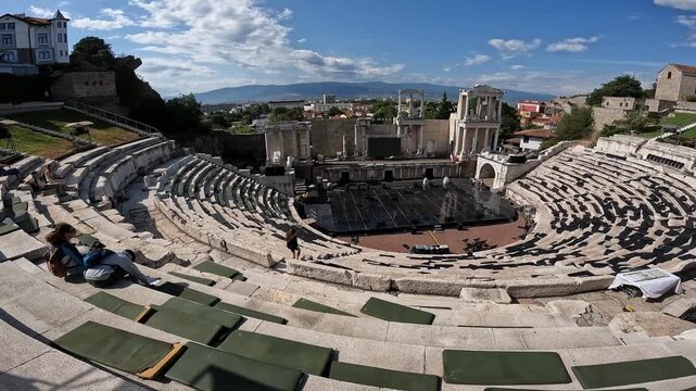 Handheld summer video with panning motion showing the Ancient Theatre of Philippopolis in Plovdiv, with surrounding hills and historic architecture in daylight. 2023