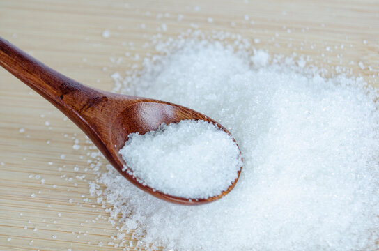 Top view of close up of salt on wooden spoon with wooden table background. Health and food concept.