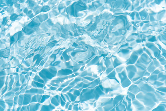 Blue water with ripples on the surface. Defocus blurred transparent blue colored clear calm water surface texture with splashes and bubbles. Water waves with shining pattern texture background.