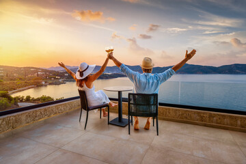 Naklejka premium A happy holiday couple enjoys the beautiful summer sunset in the mediterranean sea with a glass of wine as a concept for romantic travel