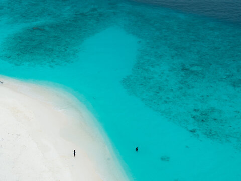 Aerial view of the pristine white sands meeting the turquoise waters, where tiny figures dot the landscape, Hoarafushi, Thiladhunmathee Uthuruburi, Maldives.