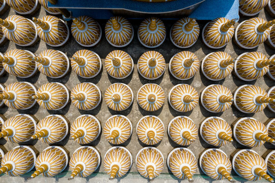 Aerial view of golden-brown and cream decorative conical objects arranged in perfect rows on a light gray surface, Tangail, Dhaka Division, Bangladesh.