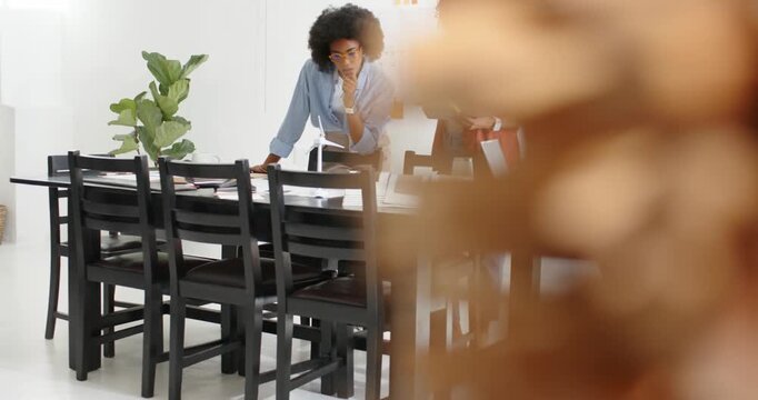 Three-woman team leaning at long wood table while camera pulling back, reviewing model for design
