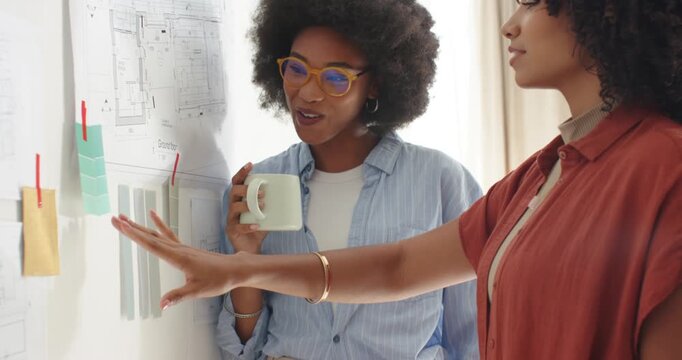 Diverse female coworkers reviewing plan in studio, right woman pointing swatches, spurring decision