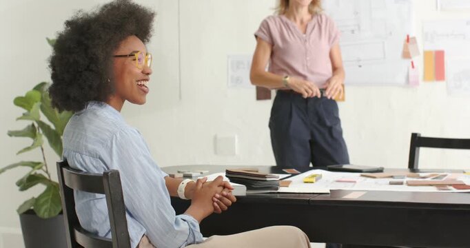 Female coworkers clapping as presenter pointing to sketches, showing samples during design meeting