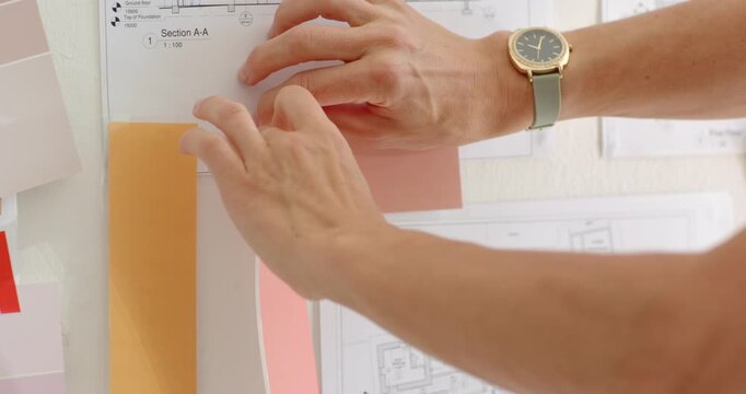 Holding elevation for layout, mid adult female arranging coral strip ochre-peach swatches on board