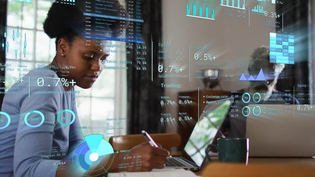 HUD overlays appearing, woman writing notes and referencing laptop while visualizing financial data