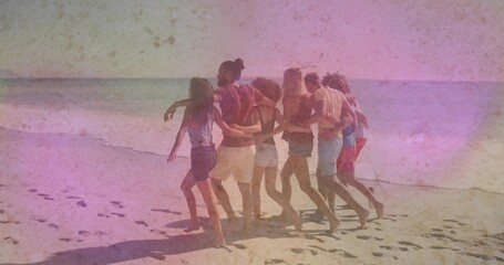 Fototapeta premium Walking seven friends linking arms and strolling along sandy shoreline with footprints, in shorts