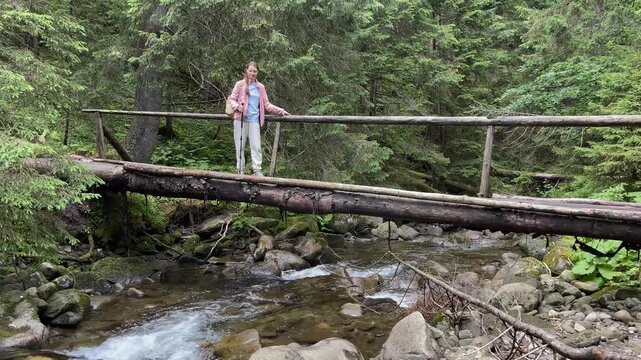 woman Explorer Crossing Bridge Over mountain Stream