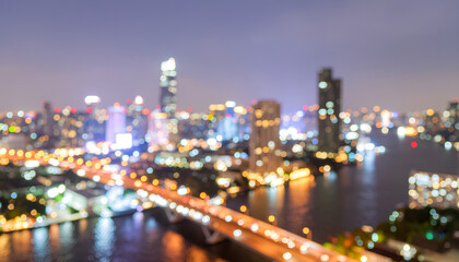 Obraz premium Defocused urban skyline with river bridge lights at night.