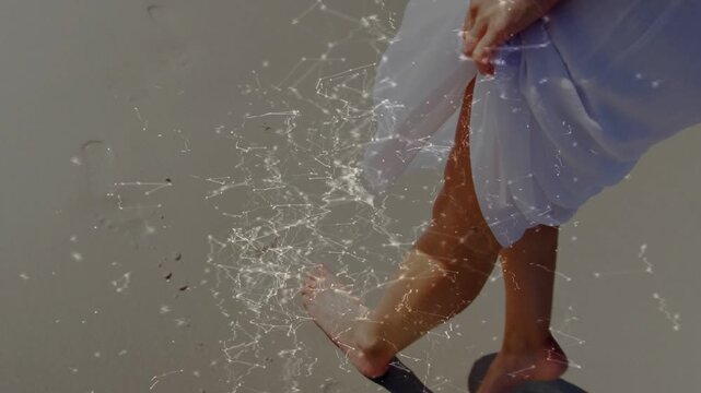 Overhead left foot landing, woman walking, keeping dress hem off sand, leaving prints, particles
