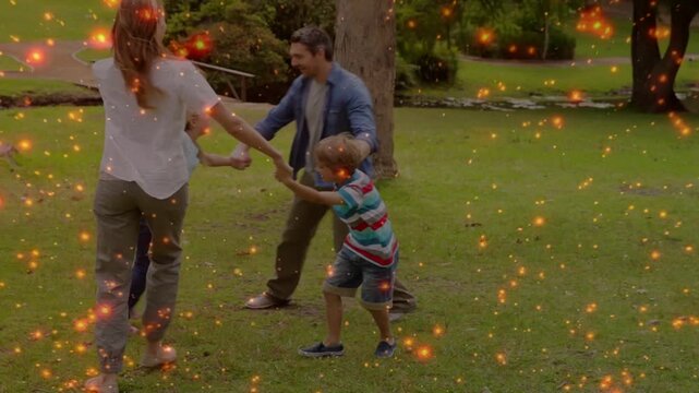Family of four taking hands and spinning on grass, spark overlay highlighting lifestyle bonding