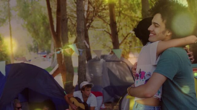 Couple hugging at camp, hearing guitar strumming, rotating holding gaze, bokeh drifting