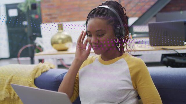 Woman on couch taking call, typing on laptop for remote work, animated waveform guiding headphones