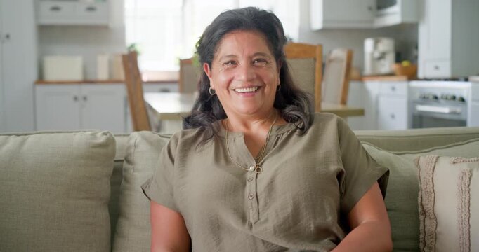 African American woman in olive blouse uncrossing legs, laughing and answering off-camera at home