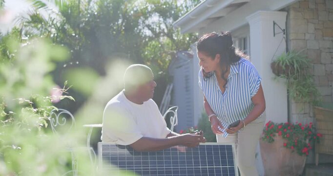 African American couple in yard he showing plug she coming holding phone checking solar panel angle