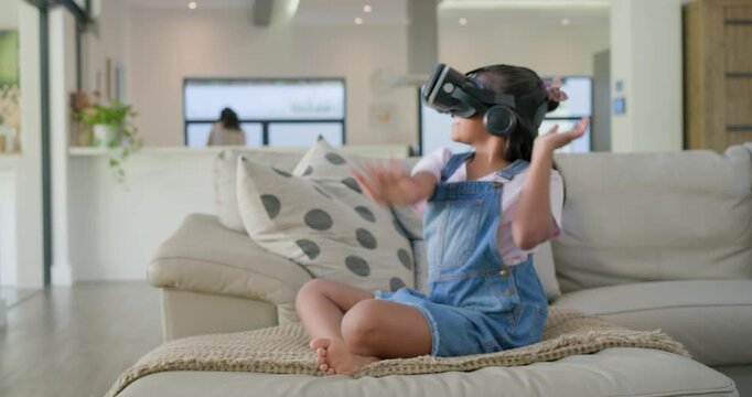 African American girl wearing VR headset headphones, making interactive VR gestures on beige sofa