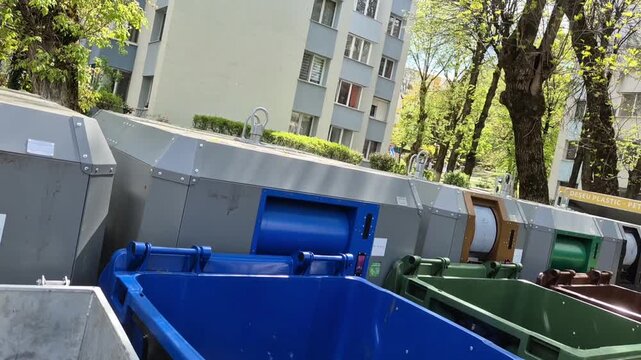 Urban recycling containers and waste sorting bins near residential buildings slow pan