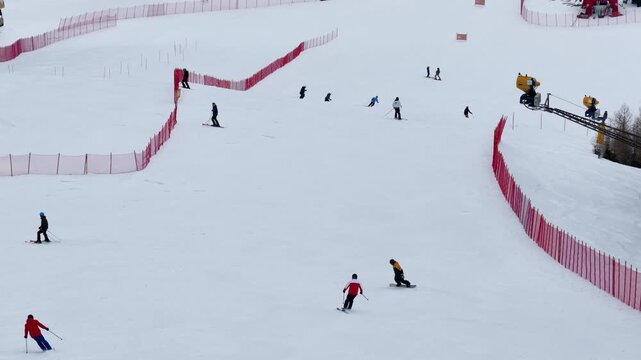 Aerial drone footage of skiers and snowboarders descending a snowy ski slope in Folgaria, Trentino, Italy, captured with a telephoto lens to highlight speed and dynamic action.