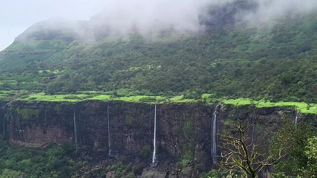 Sahyadri waterfall flows beside mighty Kulang Fort, surrounded by misty cliffs and lush green valleys. A breathtaking 4K monsoon view of raw wilderness, power, and timeless mountain beauty.