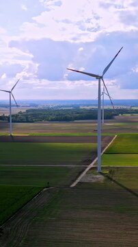 Aerial view of view of large fields with electric windmills in the afternoon sun