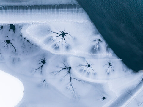 Winter landscape, aerial view of frozen lake with ice cracks, nature background, destination concept. Fusine lakes, Tarvisio, Friuli, Italy.