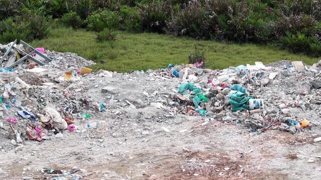 Aerial footage showing an outdoor rubbish dump with construction debris and scattered plastic waste.