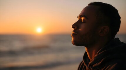 Fototapeta premium A contemplative man stands in profile against the vivid ocean horizon during a dramatic sunset embracing a moment of natural peace