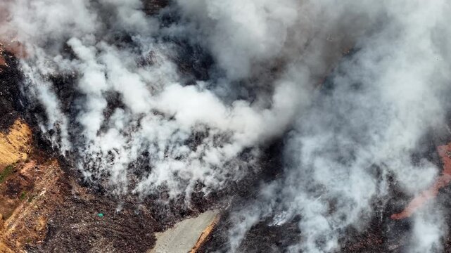 Aerial drone footage of burning landfill site and smoke