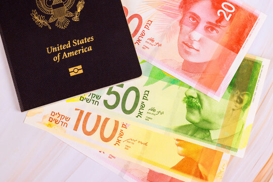 United States passport next to different New Israeli shekel banknotes on table, preparation for travel.