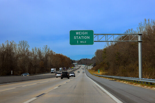 Cars travel along American highway with weigh station sign indicating one mile ahead.