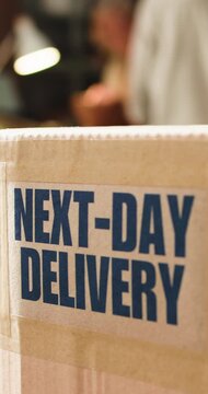 Logistics, box or shipping label in office, package distribution or rush order for next day delivery. Freight, supply chain and parcel with express sticker to streamline transport, startup and people