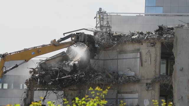 Demolition of reinforced concrete structure, gutting and renovation, hydraulic hammer dismantles building, caterpillar excavator machine at construction site