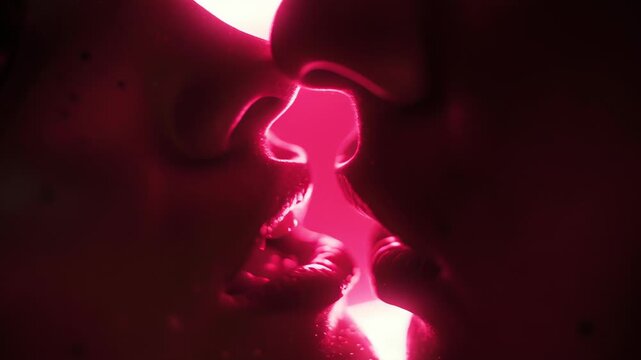 Romantic close-up of passionate kiss illuminated by soft pink neon light in intimate moment
