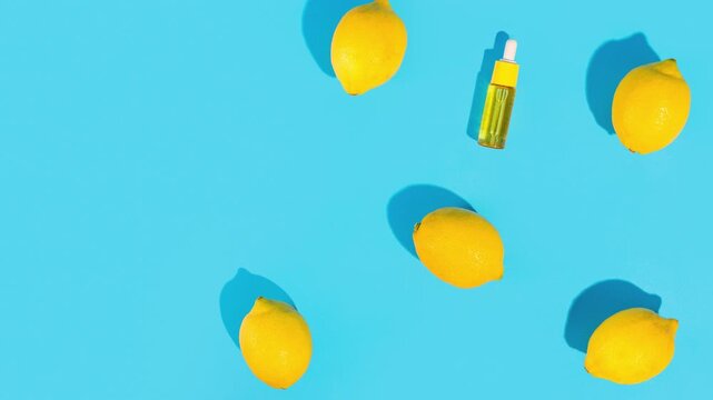 Bright yellow lemons and serum bottle arranged on a vibrant blue background