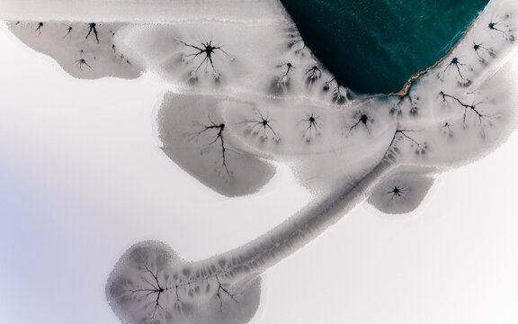 Landscape, aerial view of frozen lake with cracks and turquoise water, abstract nature pattern, destination concept. Fusine lakes, Tarvisio, Friuli, Italy.
