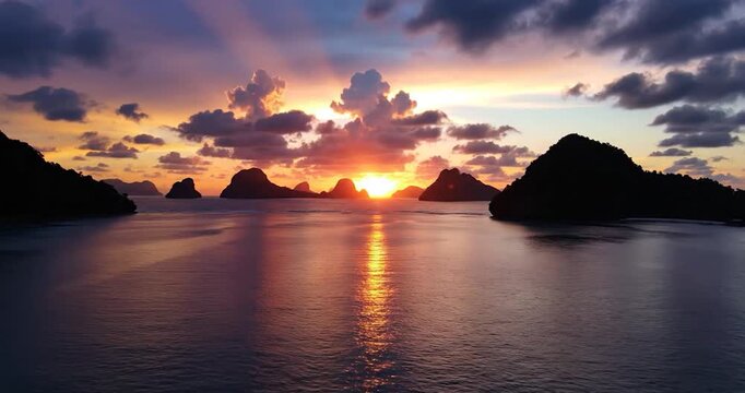 Tropical sunset over limestone islands in the ocean at dusk