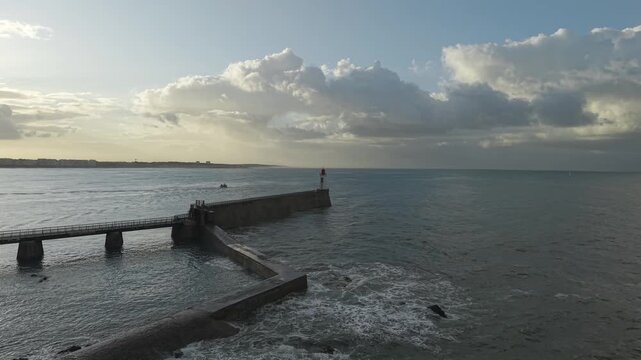Jetty and breakwater at golden hour, dramatic clouds and sunlight, Les Sables-d'Olonne harbor entrance