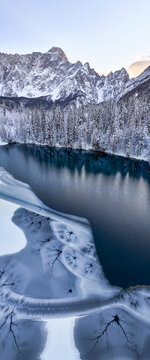 Winter landscape, aerial view of frozen lake and snow-covered mountains, the wild Mangart mountain group, tourism and destination concept, Fusine lakes, Tarvisio, Friuli, Italy.