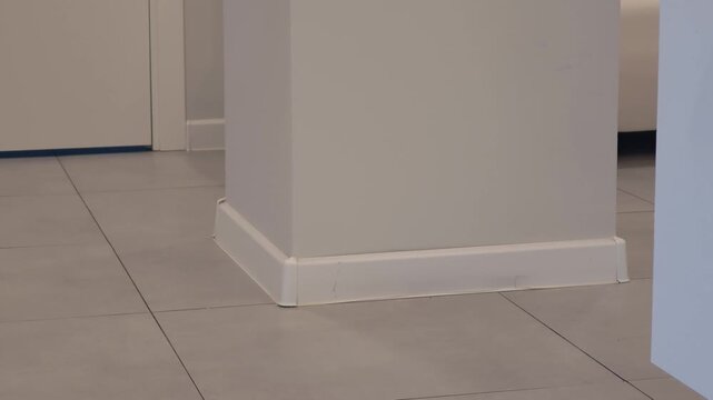 White interior corner showcasing a column with a baseboard and tiled floor, highlighting the gradual shift in perspective and details across the three frames in a modern setting