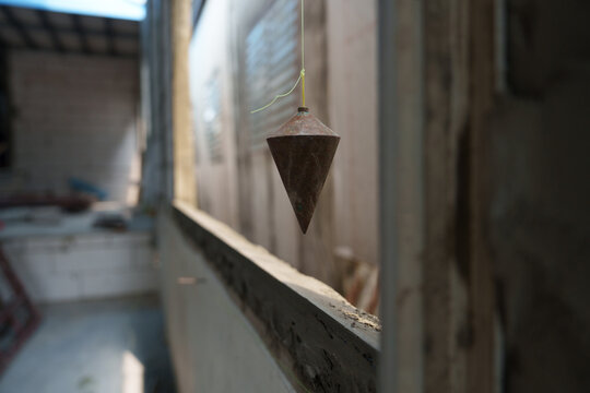 The focus is on using plumb bobs in plastering and working on construction projects.