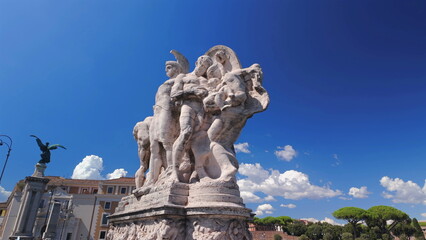 Obraz premium Marble war monument depicting muscular soldiers and heroic figures against deep blue sky in Rome, Italy, representing classical European history and military valor
