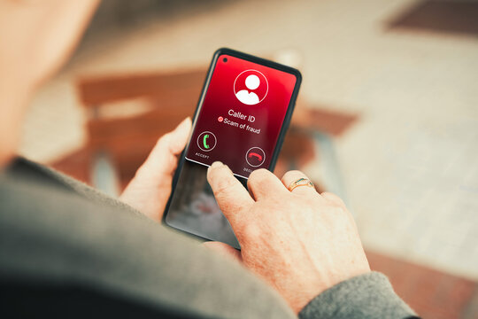 Fraud Caller ID Warning on Red Smartphone Screen Held by Senior Woman. Cybersecurity awareness, consumer protection, telecom advertising, and phone scams.