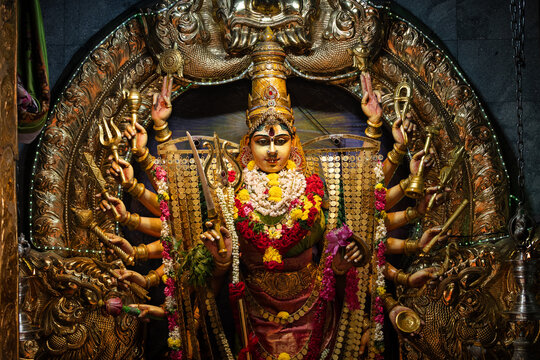 Closeup of an ornate, golden statue of the 18-armed Hindu deity Sri Lakshmi Durgai in the Sri Veeramakaliamman Temple in the Little India district of Singapore. 
