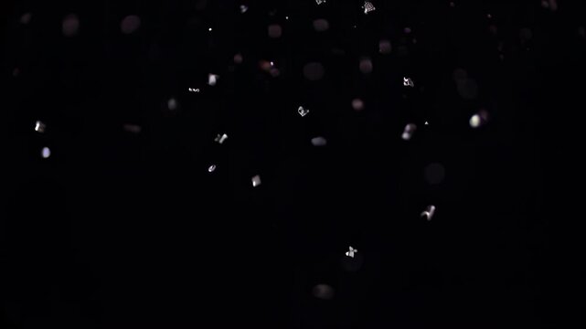 White dust particles floating in the dark on a black background.